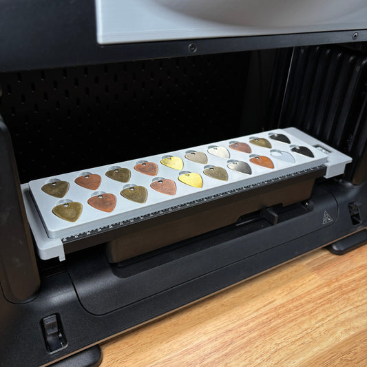Samcraft guitar pick jig on the eufyMake E1 print bed, holding rows of metal guitar picks in brass, copper, gold and gunmetal finishes.