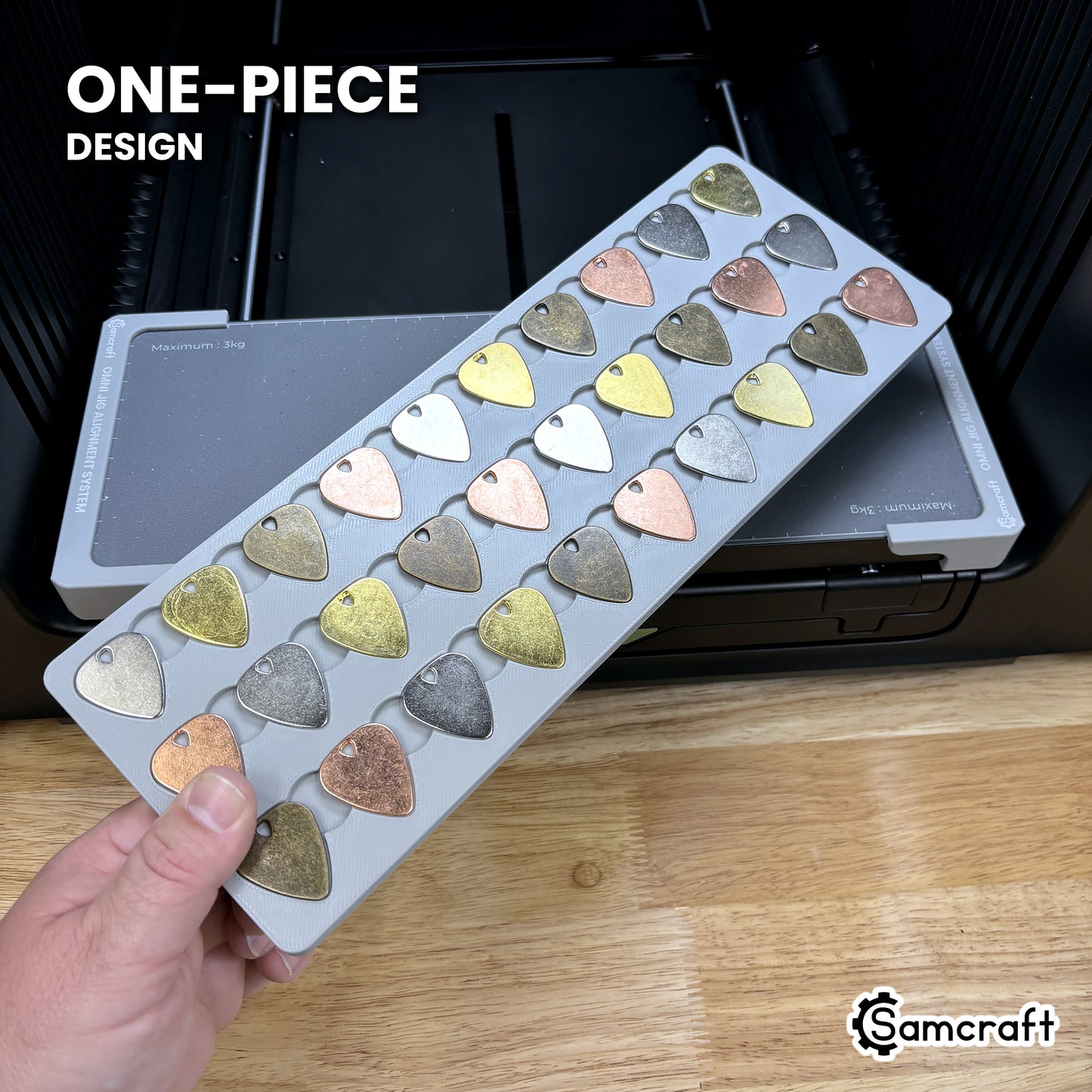 Hand holding the one-piece Samcraft guitar pick jig for the xTool Omni, every pick pocket in a single molded tray.