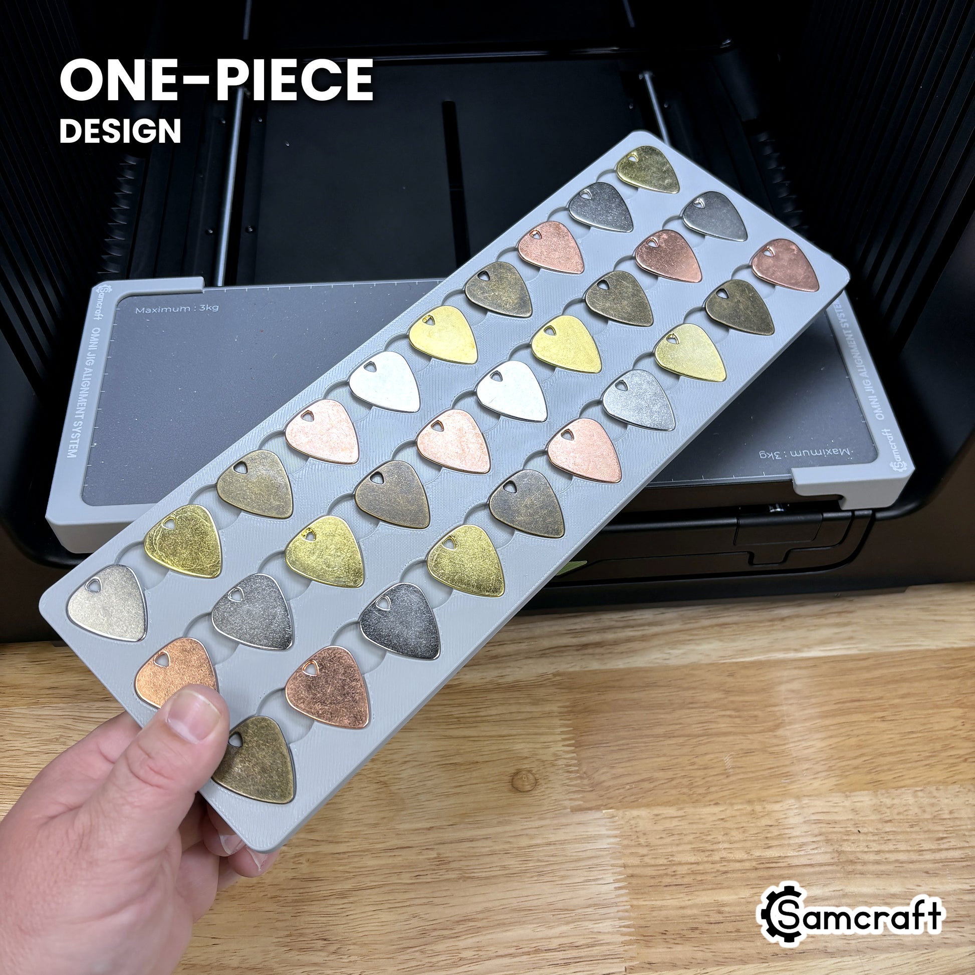 Hand holding the one-piece Samcraft guitar pick jig for the xTool Omni, every pick pocket in a single molded tray.