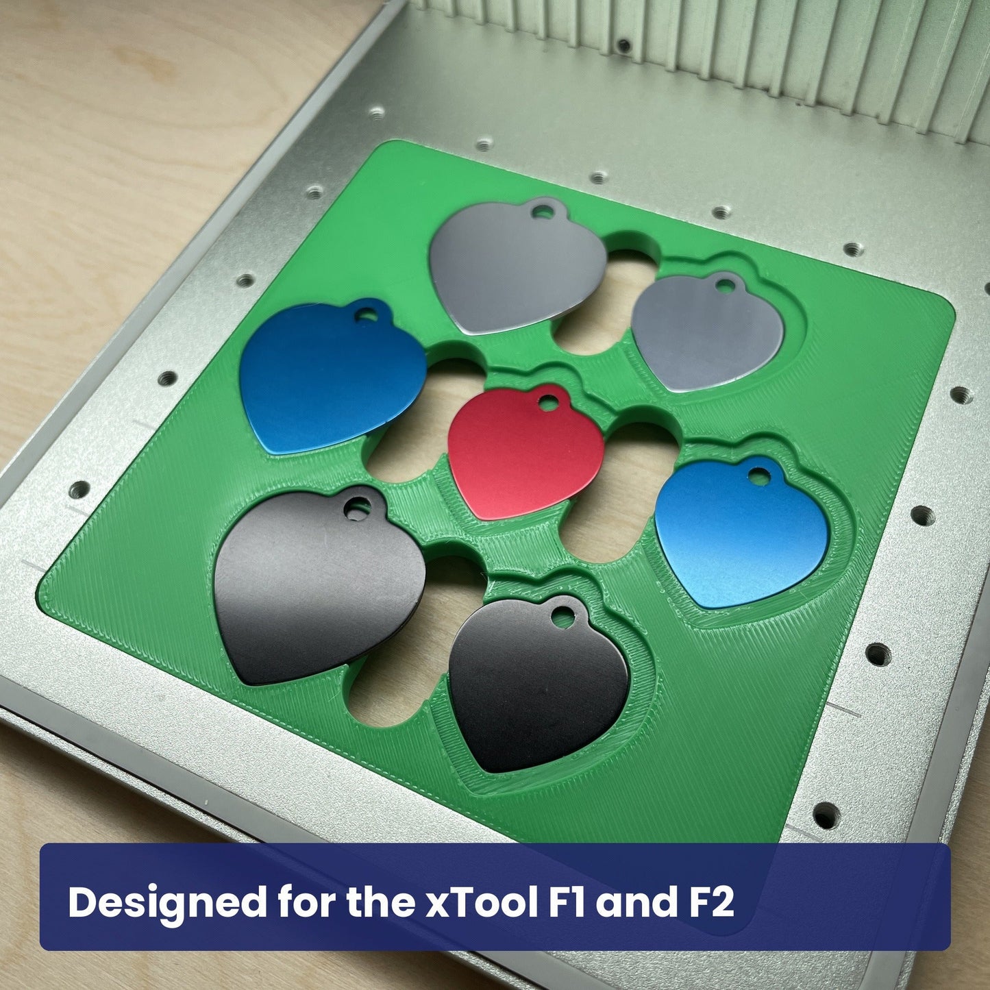 Green Samcraft heart pet tag jig seated in the xTool F1 base plate, loaded with seven coloured heart tags.