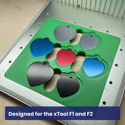 Green Samcraft heart pet tag jig seated in the xTool F1 base plate, loaded with seven coloured heart tags.