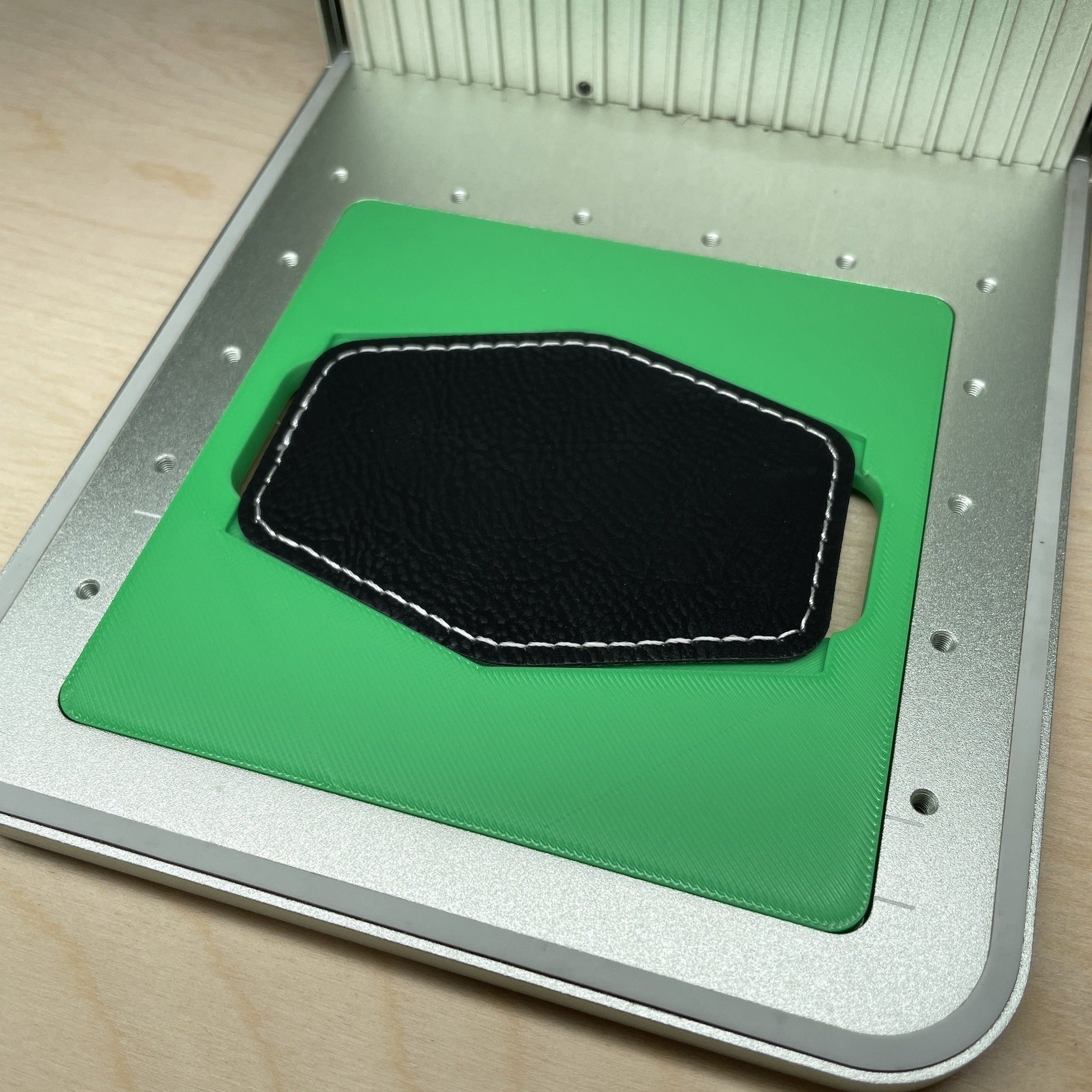 Samcraft hex patch jig in an xTool F1 laser bed, holding a black hexagonal leatherette patch.