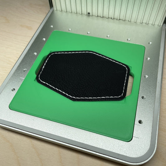 Samcraft hex patch jig in an xTool F1 laser bed, holding a black hexagonal leatherette patch.