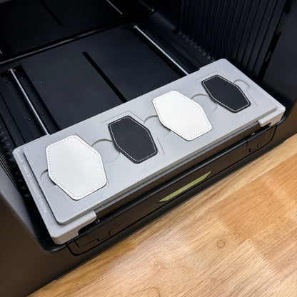 Samcraft hex patch jig on the bed of an xTool Omni UV printer, loaded with four hexagon leatherette patches.