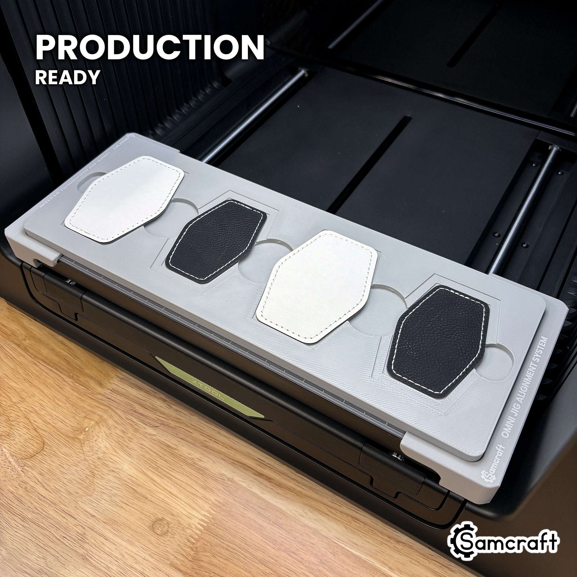 Samcraft hex patch jig loaded with four hexagon leatherette patches on the xTool Omni UV printer bed, set up for production runs.