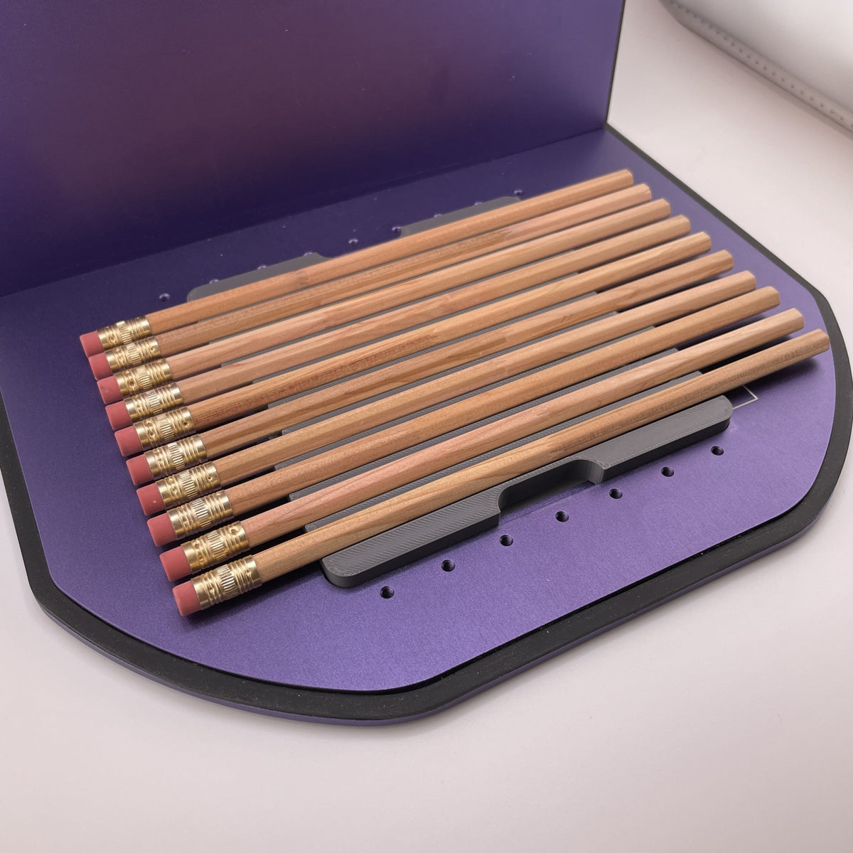 Samcraft hexagon pencil jig on the purple bed of a WeCreat Lumos, holding a full row of wooden pencils.