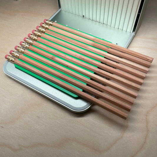 Samcraft green hexagon pencil jig in an xTool F1 laser bed, holding a full row of wooden pencils side by side.