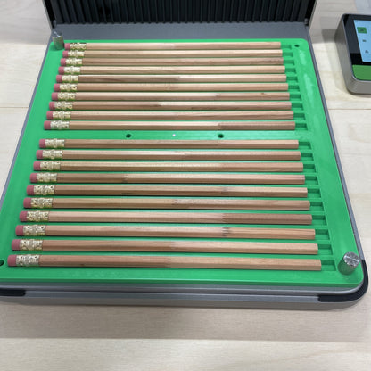 Samcraft green hexagon pencil jig in an xTool F1 Ultra laser bed, holding a full row of wooden pencils.