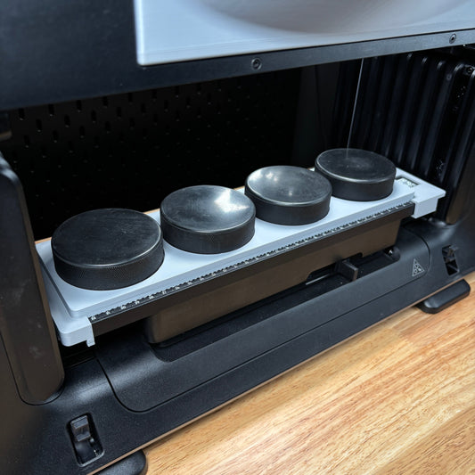 Samcraft hockey puck jig on the eufyMake E1 print bed, holding four black hockey pucks in round recesses.