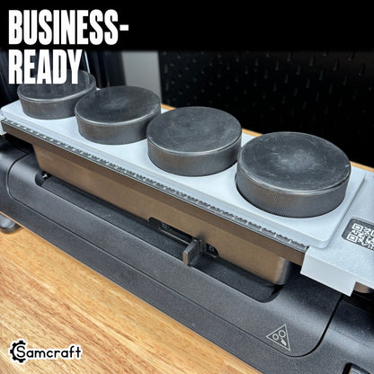 Hockey Puck Jig for the eufyMake E1 — four black hockey pucks seated in the gray 3D-printed tray with built-in alignment ruler, ready for business-scale personalization.