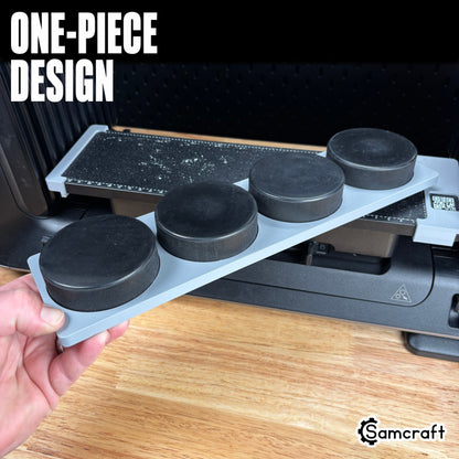 Hockey Puck Jig for the eufyMake E1 — hand holding the gray one-piece 3D-printed tray loaded with four black hockey pucks in their round molded pockets, with the built-in measurement ruler, showing the solid single-piece design.