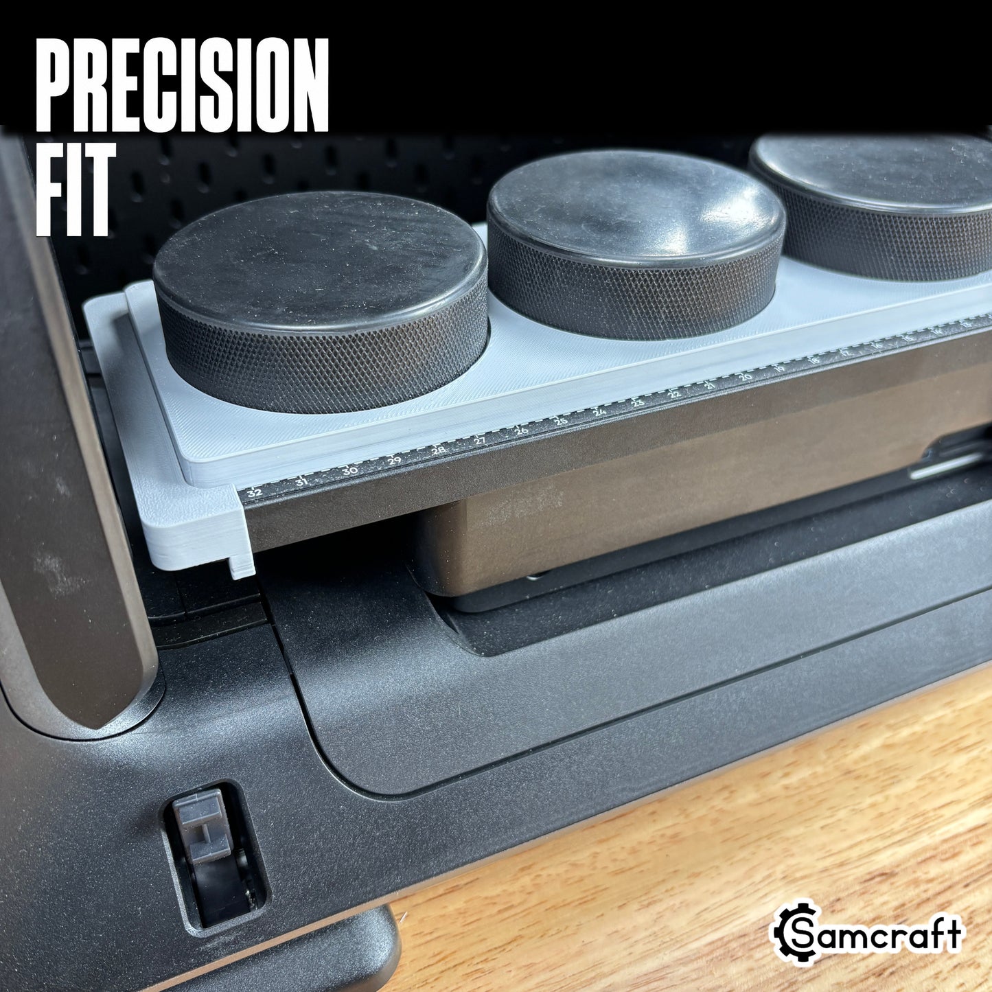 Hockey Puck Jig for the eufyMake E1 — close-up of black hockey pucks sitting flush in the round recessed pockets of the gray 3D-printed tray, with the built-in measurement ruler visible, showing the precision fit.