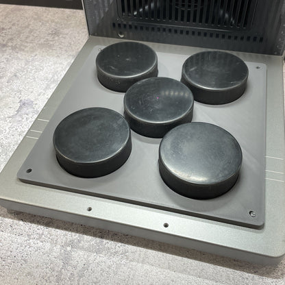 Samcraft hockey puck jig on the xTool F2 Ultra bed, holding five regulation black hockey pucks.