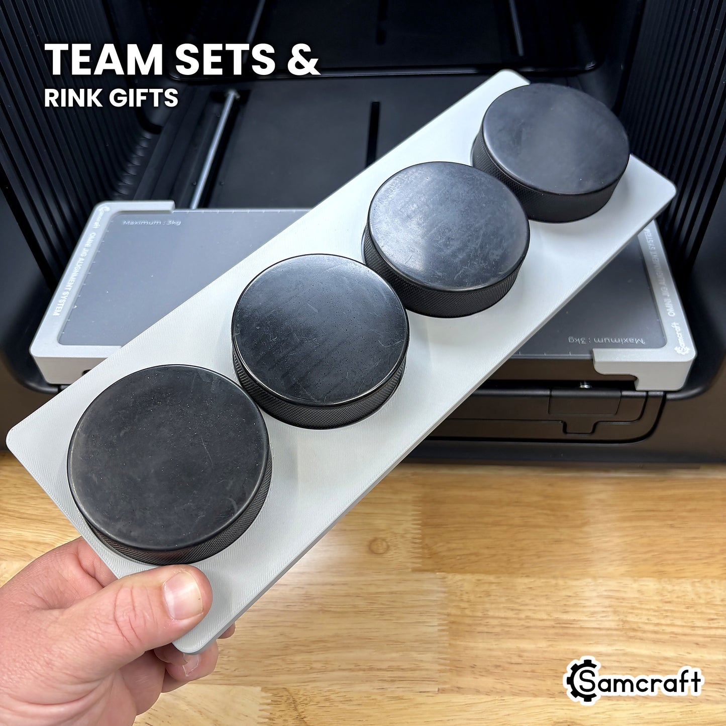 Hand holding the Samcraft xTool Omni hockey puck jig loaded with four regulation pucks, ready for team sets and rink gifts.