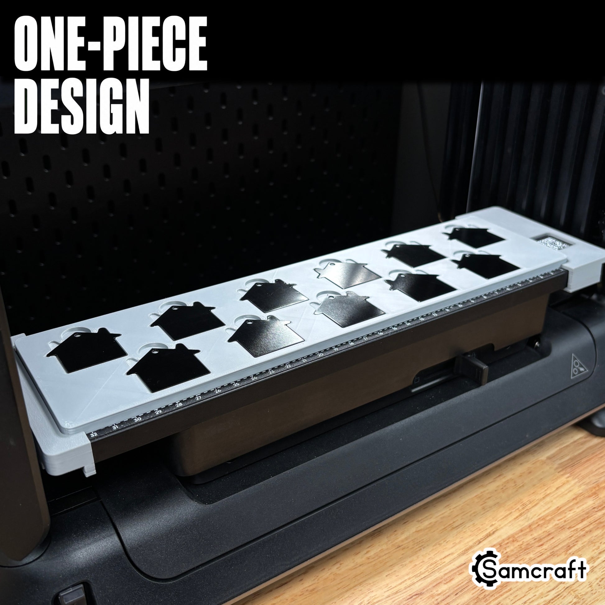 Samcraft House Tag Keychain Jig holding black and silver house-shaped keychain blanks in a one-piece gray 3D-printed tray on the eufyMake E1 UV printer.