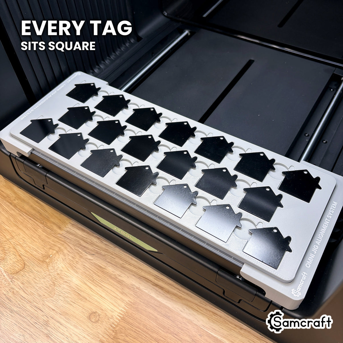 Every house tag seated square in its own pocket across the Samcraft xTool Omni jig, for consistent print placement.