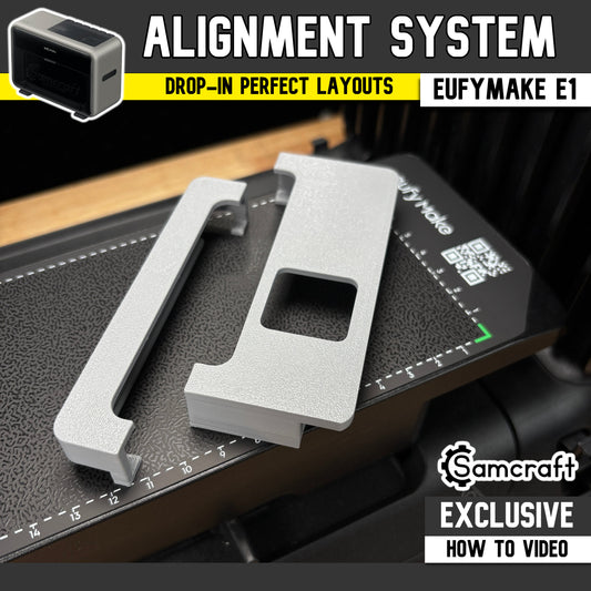 Jig Alignment System for the eufyMake E1 UV printer — two gray 3D-printed alignment guides, an edge rail and a corner bracket with a square cutout, set on the printer's black textured bed for drop-in perfect jig layouts; an original Samcraft design with an exclusive how-to video.