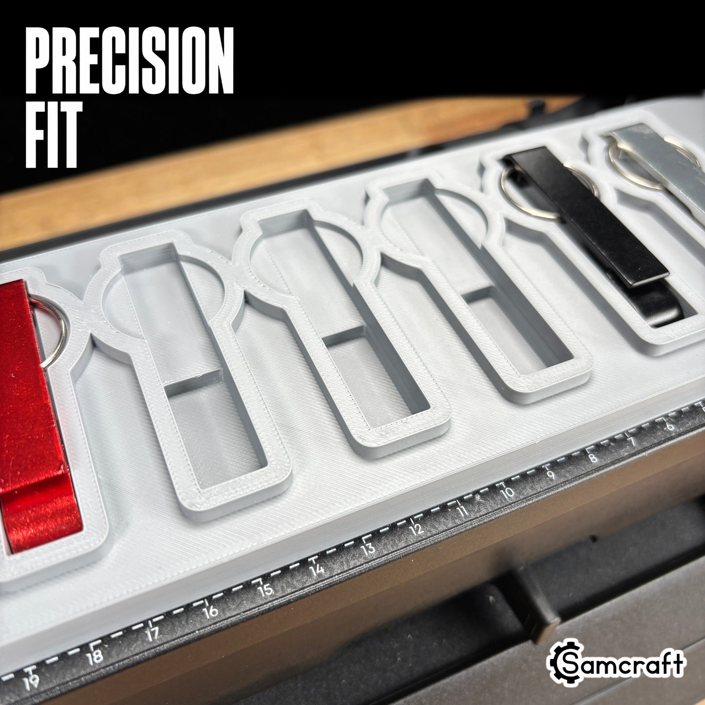 Keychain Bottle Opener Jig for the eufyMake E1 — close-up of metal keychain bottle openers sitting flush in the shaped recessed pockets of the gray 3D-printed tray, with empty pockets and the built-in ruler visible, showing the precision-engineered fit.