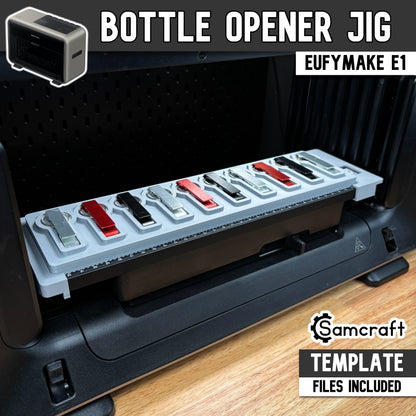 Keychain Bottle Opener Jig for the eufyMake E1 UV printer — gray one-piece 3D-printed tray holding a row of metal keychain bottle openers in silver, black, and red finishes, each with a split key ring seated in a shaped recessed pocket, with a built-in alignment ruler along the front edge; template files included.