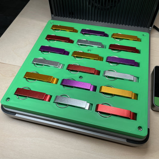 Samcraft green keychain bottle opener jig in an xTool F1 Ultra laser bed, holding metal keychain bottle openers in mixed finishes.