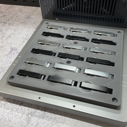Samcraft keychain bottle opener jig on the xTool F2 Ultra bed, holding rows of metal keychain bottle openers.