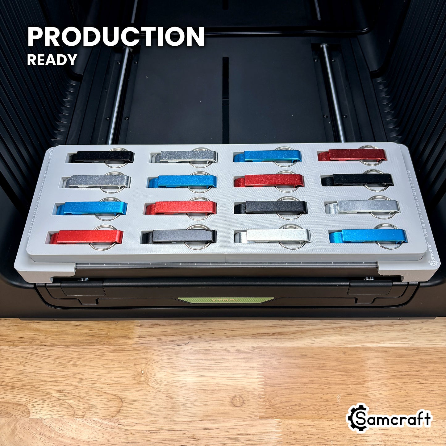 Samcraft keychain bottle opener jig loaded with sixteen openers on the xTool Omni printer bed, set up for production runs.