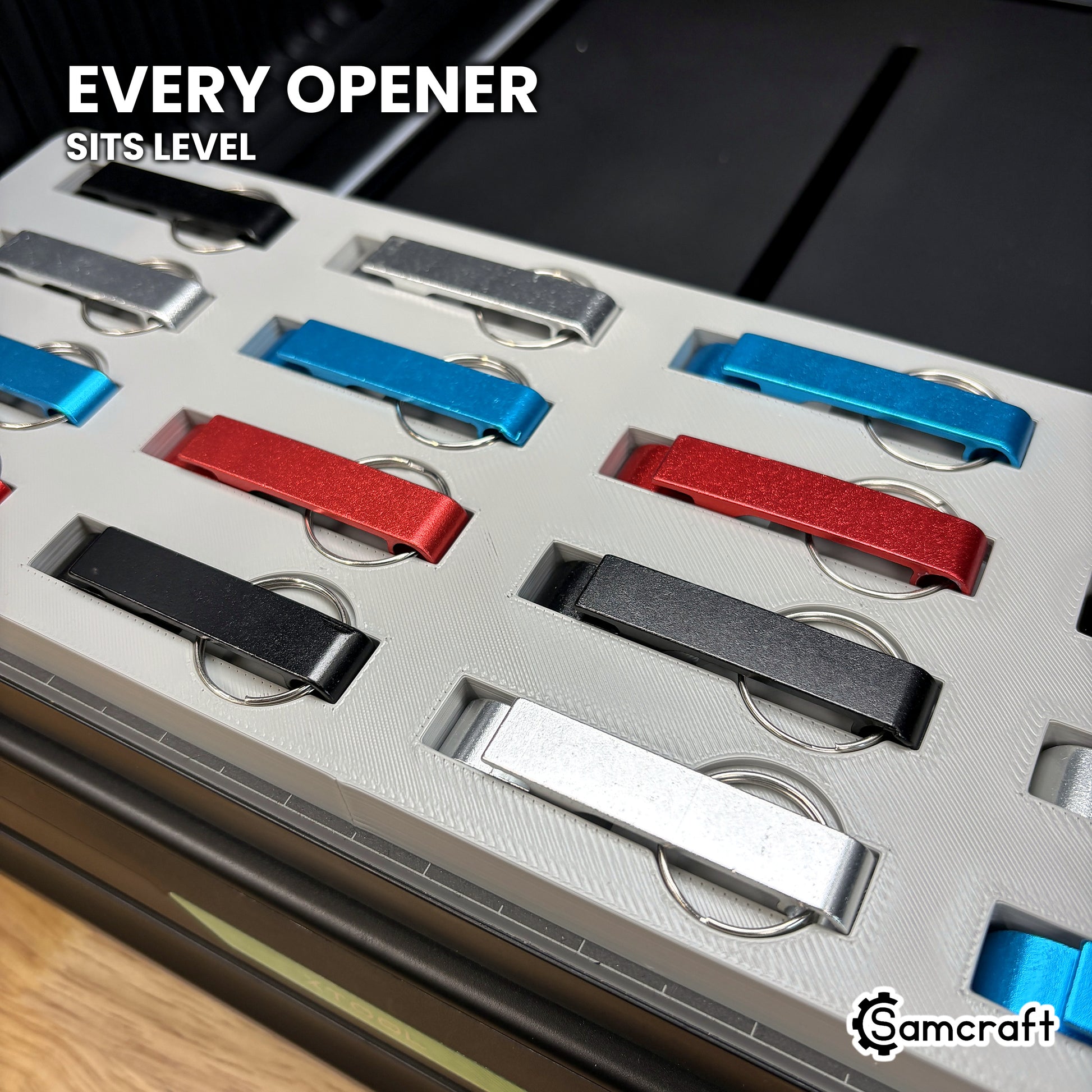 Angled close-up of aluminum keychain bottle openers sitting level in the Samcraft xTool Omni jig for consistent print height.