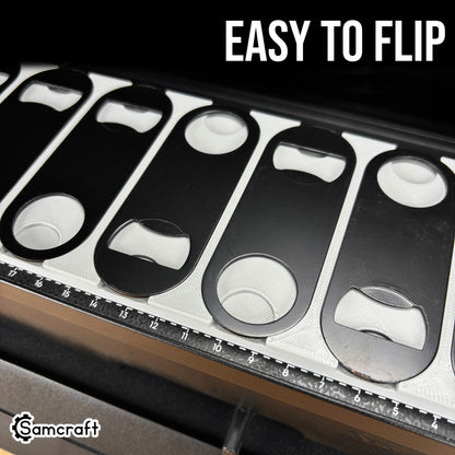 Oval Metal Bottle Opener Keychain Jig for the eufyMake E1 — close-up of the gray 3D-printed tray pockets with black oval bottle openers, some flipped to show both orientations, highlighting how easy they are to flip.