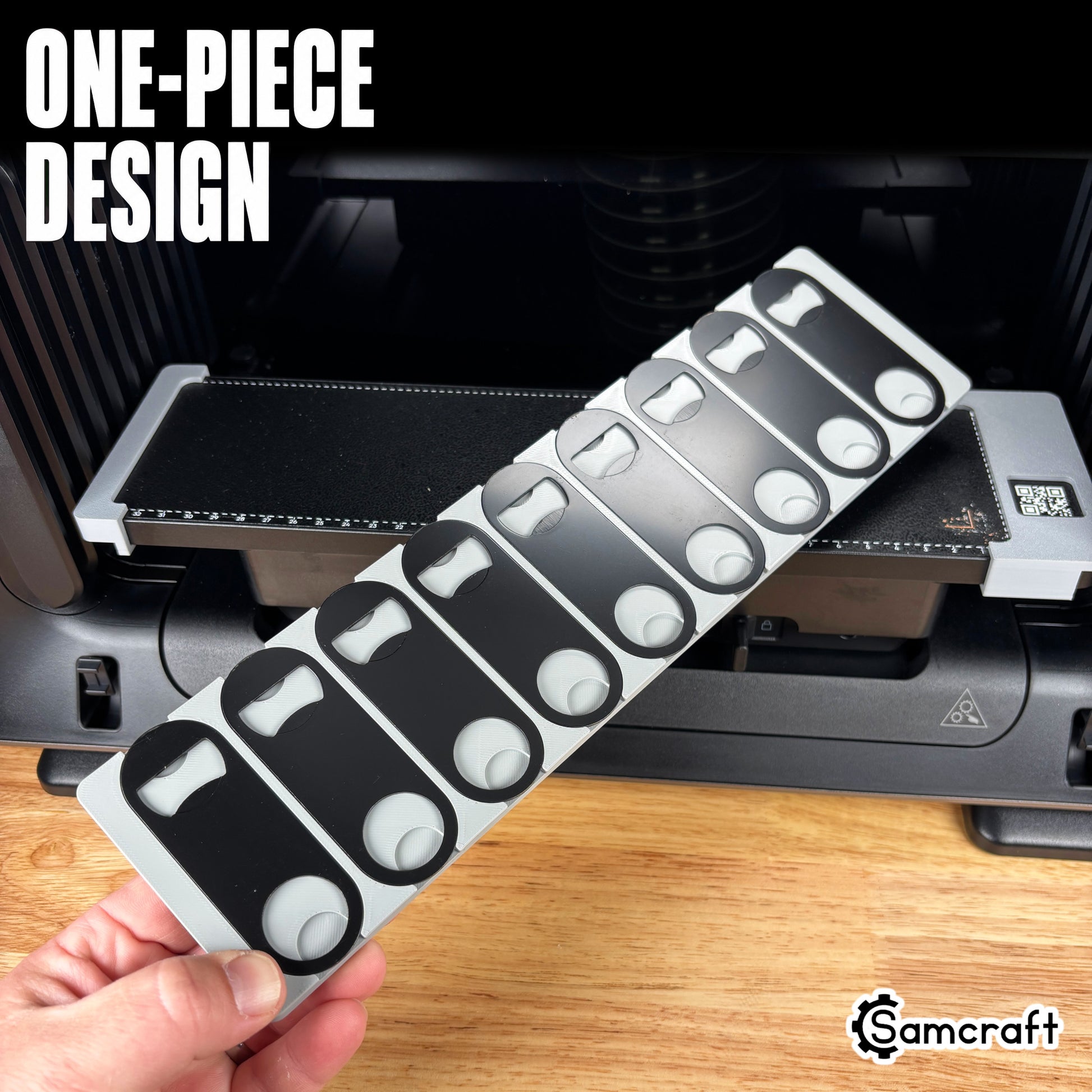 Oval Metal Bottle Opener Keychain Jig for the eufyMake E1 — hand holding the gray one-piece 3D-printed tray with shaped pockets for oval metal bottle openers, template files included, highlighting the one-piece design.