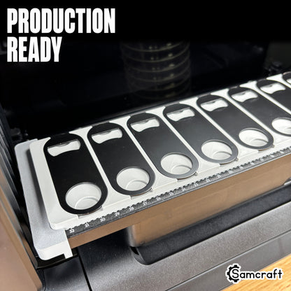Oval Metal Bottle Opener Keychain Jig for the eufyMake E1 — close-up angled view of the gray 3D-printed tray with black oval bottle openers seated in shaped pockets on the printer bed with built-in alignment ruler, highlighting the production-ready design.