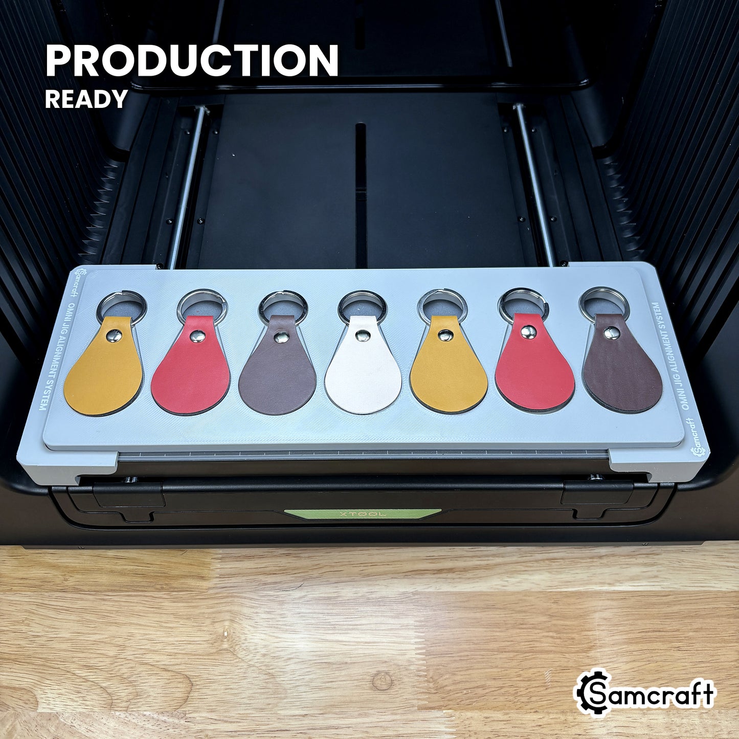 Samcraft leather key fob jig loaded with seven fobs on the xTool Omni printer bed, set up for production runs.