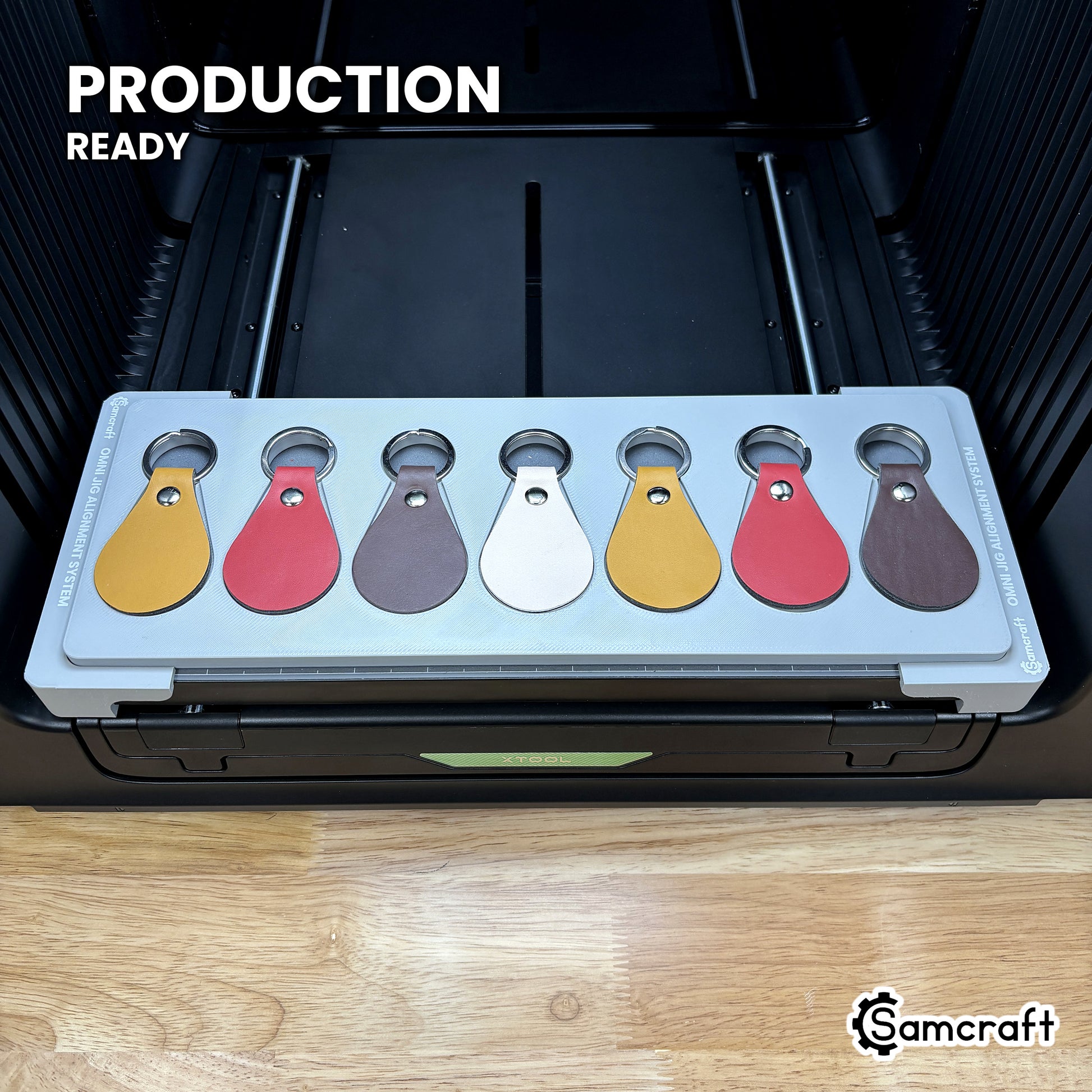 Samcraft leather key fob jig loaded with seven fobs on the xTool Omni printer bed, set up for production runs.