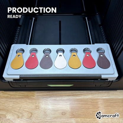 Samcraft leather key fob jig loaded with seven fobs on the xTool Omni printer bed, set up for production runs.