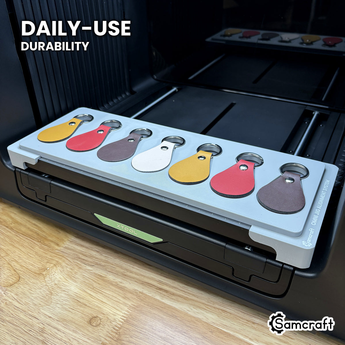 Samcraft leather key fob jig in high-temperature rated plastic holding seven leather fobs on the xTool Omni bed, built for daily use.