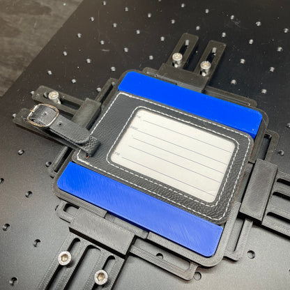 Samcraft blue leatherette luggage tag jig on a ComMarker laser bed, holding a cream leatherette luggage tag.