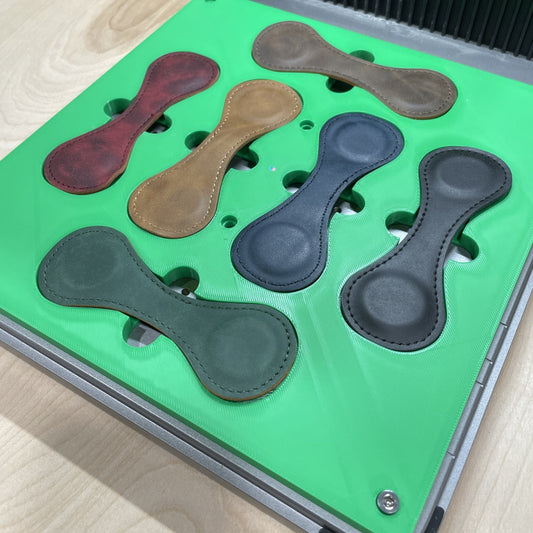 Samcraft green magnetic bookmark jig in an xTool F1 Ultra laser bed, holding wrap-style leather bookmarks in red, tan, grey and green.