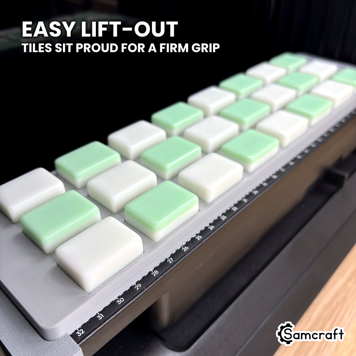 Close-up of white and green mahjong tiles standing above the shallow pockets of the Samcraft eufyMake E1 jig, easy to grip and lift out.