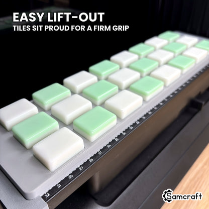 Close-up of white and green mahjong tiles standing above the shallow pockets of the Samcraft eufyMake E1 jig, easy to grip and lift out.