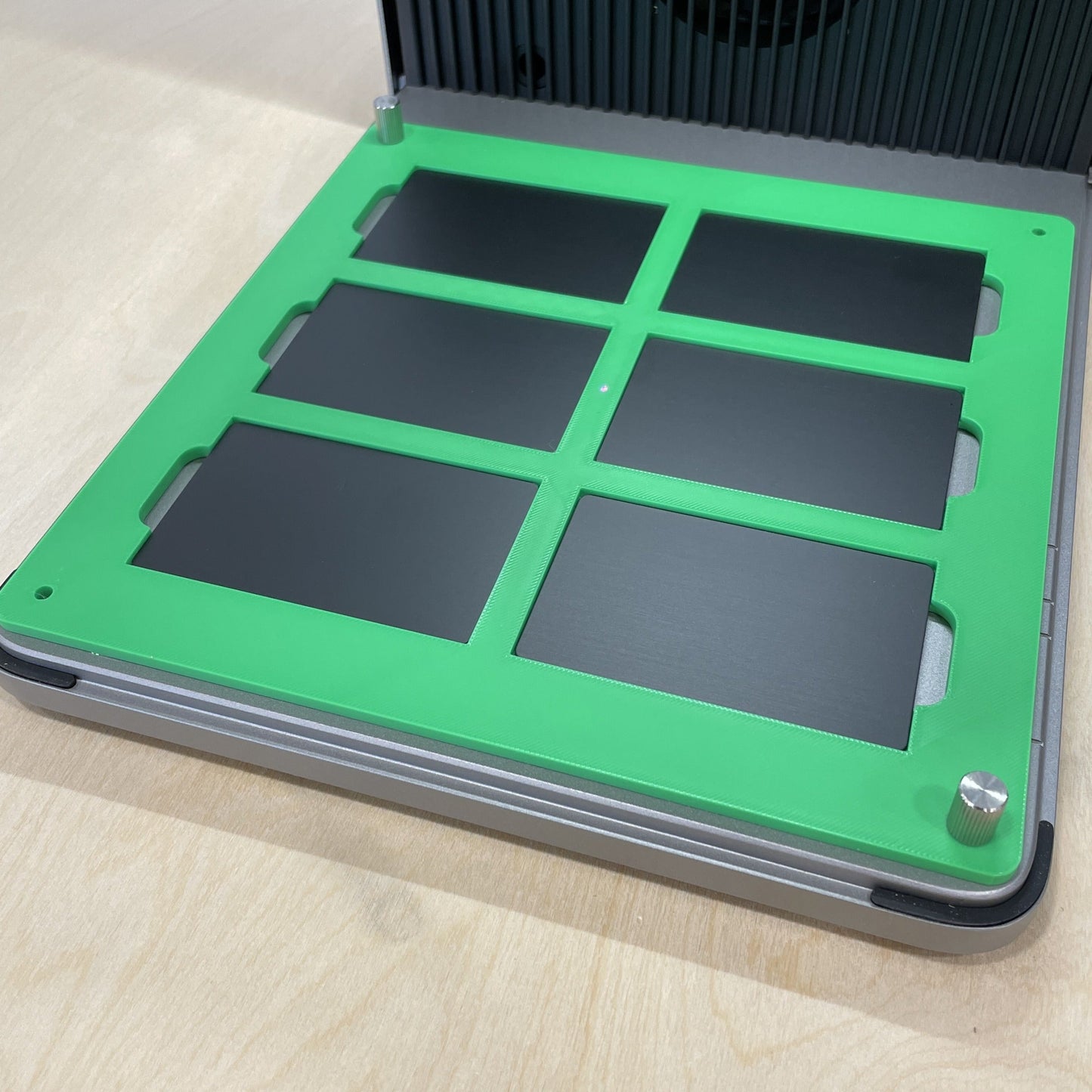 Samcraft green metal business card jig in an xTool F1 Ultra laser bed, holding six black metal business cards.