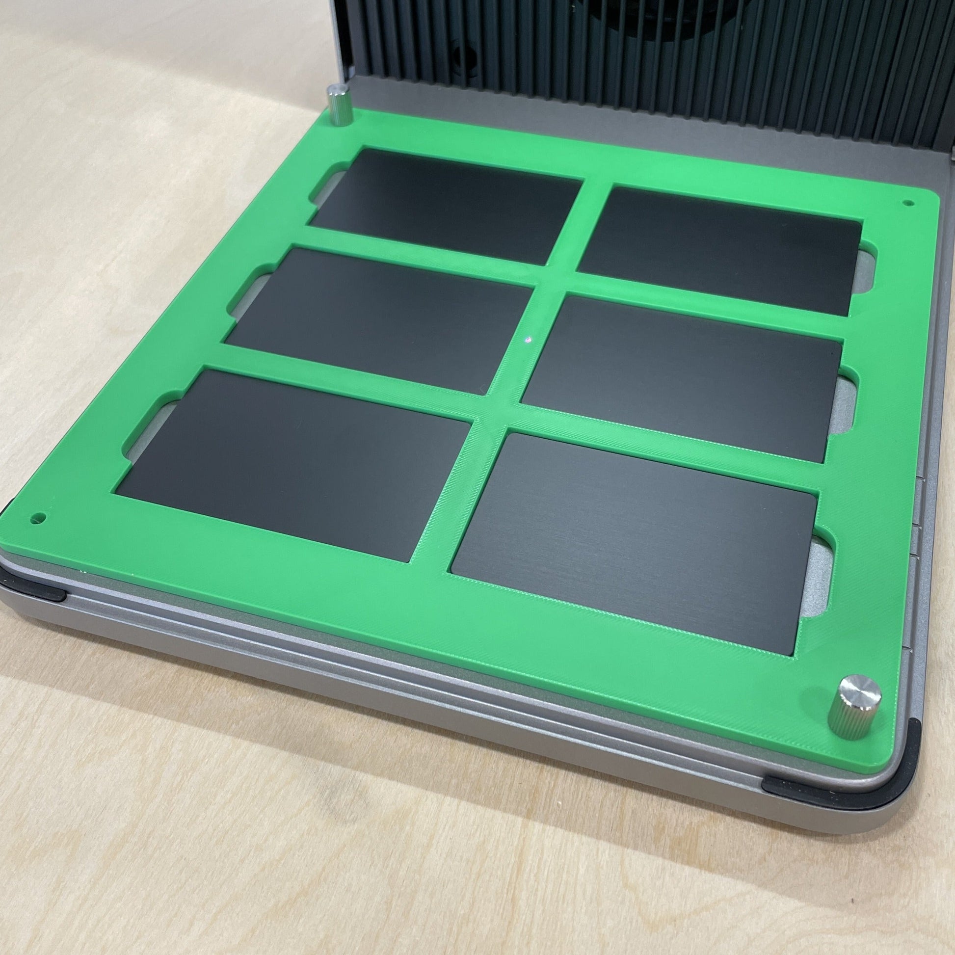 Samcraft green metal business card jig in an xTool F1 Ultra laser bed, holding six black metal business cards.