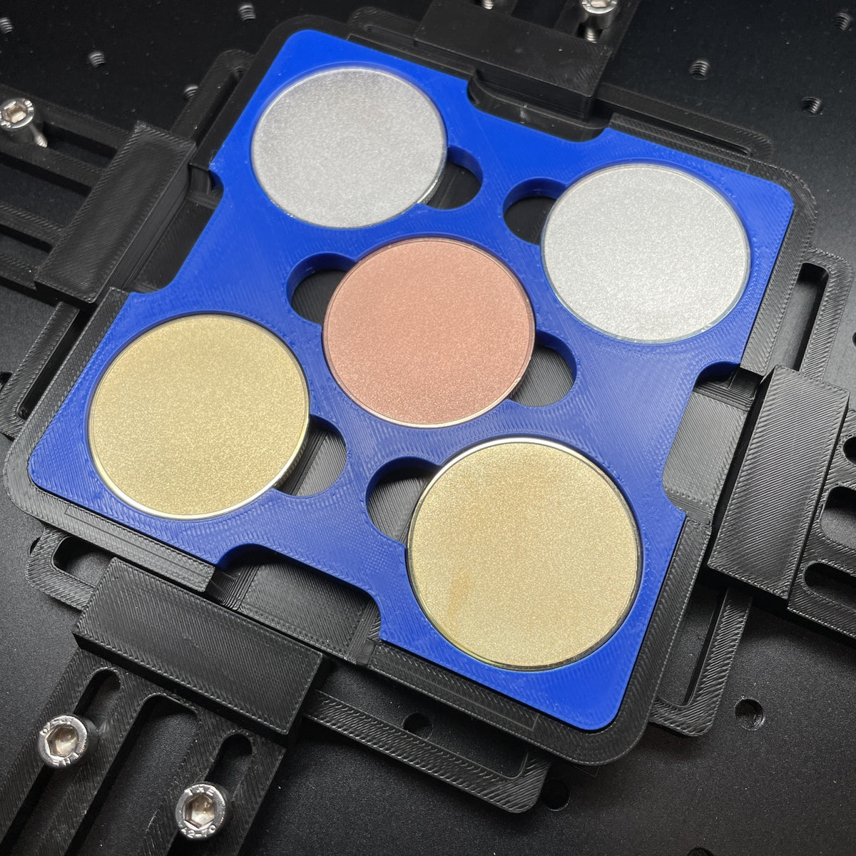 Samcraft blue 40mm metal coin jig on a ComMarker bed, holding gold, silver and copper coin blanks.