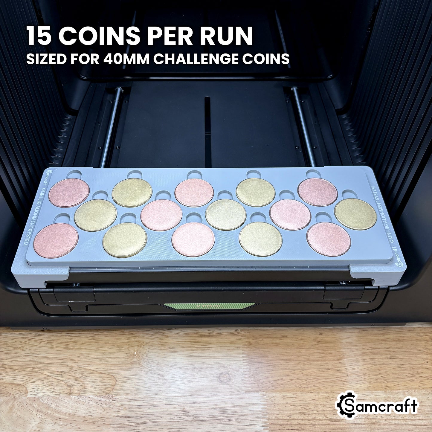 Samcraft 40mm metal coin jig loaded with fifteen blank challenge coins in three staggered rows of five, a full run in a single pass on the xTool Omni.