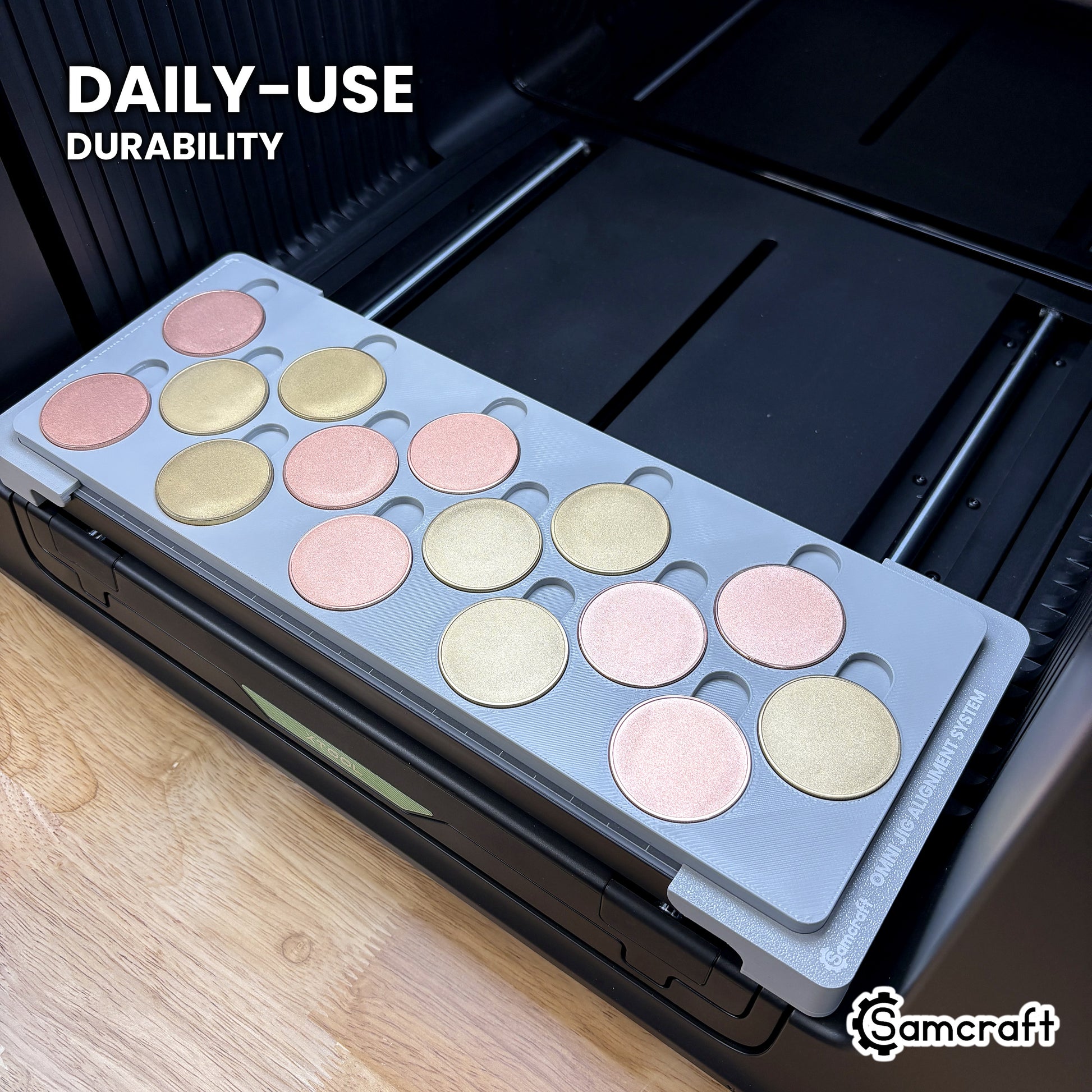 Samcraft 40mm metal coin jig in high-temperature rated plastic holding blank rose gold and gold coins on the xTool Omni bed, built for daily-use durability.
