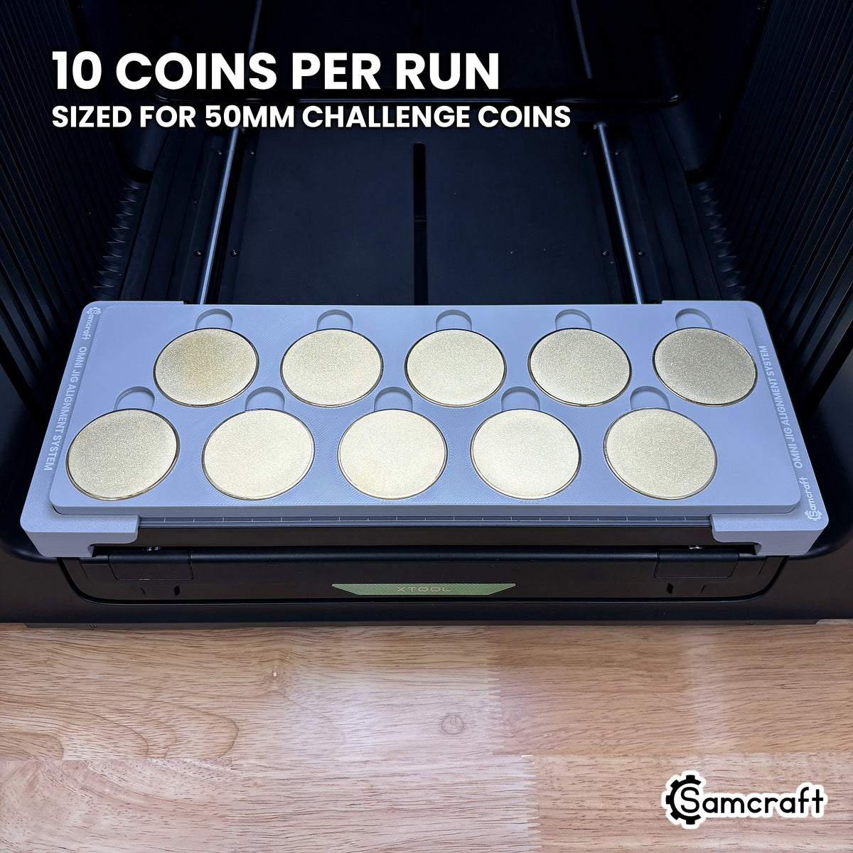 Samcraft 50mm metal coin jig loaded with ten blank challenge coins in two staggered rows of five, a full run in a single pass on the xTool Omni.