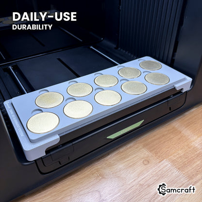 Samcraft 50mm metal coin jig in high-temperature rated plastic holding blank gold coins on the xTool Omni bed, built for daily-use durability.