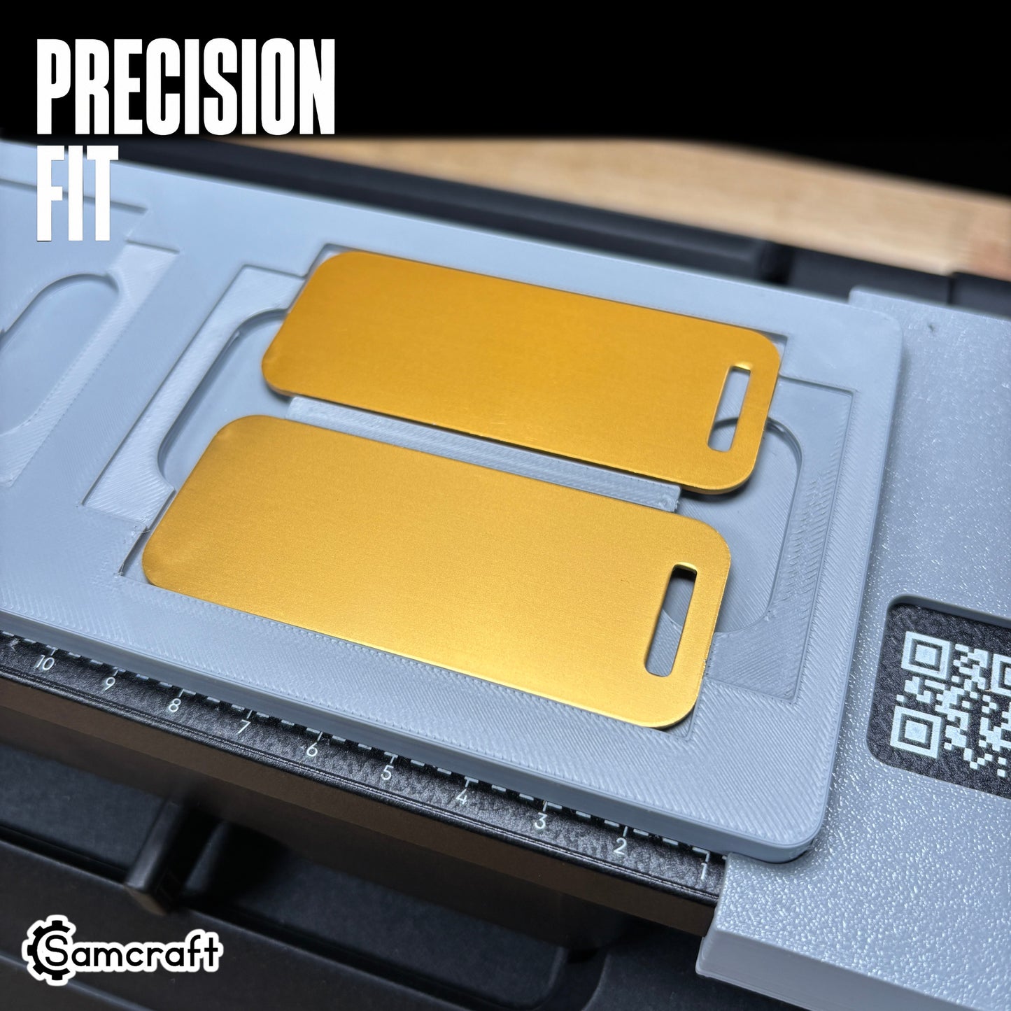 Detail shot of two gold metal luggage tags seated in the Samcraft jig's precision-fit recessed pocket, highlighting tight tolerance on the eufyMake E1.