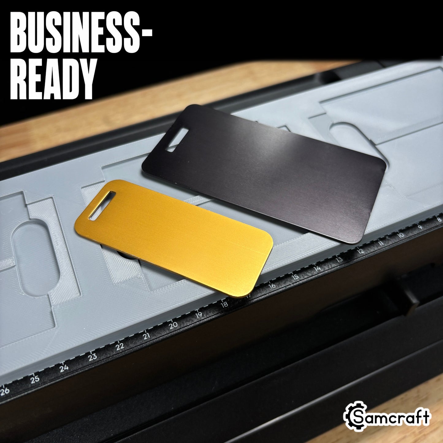 Close-up of gold and black anodized aluminum luggage tags with strap slots resting on the Samcraft jig, showing the eufyMake E1 print bed and alignment ruler.
