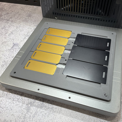 Samcraft metal luggage tag jig on the xTool F2 Ultra bed, holding gold and black metal luggage tags.