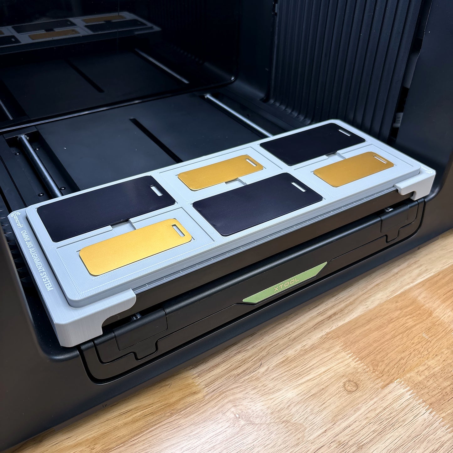Samcraft metal luggage tag jig on the bed of an xTool Omni UV printer, loaded with six tags.