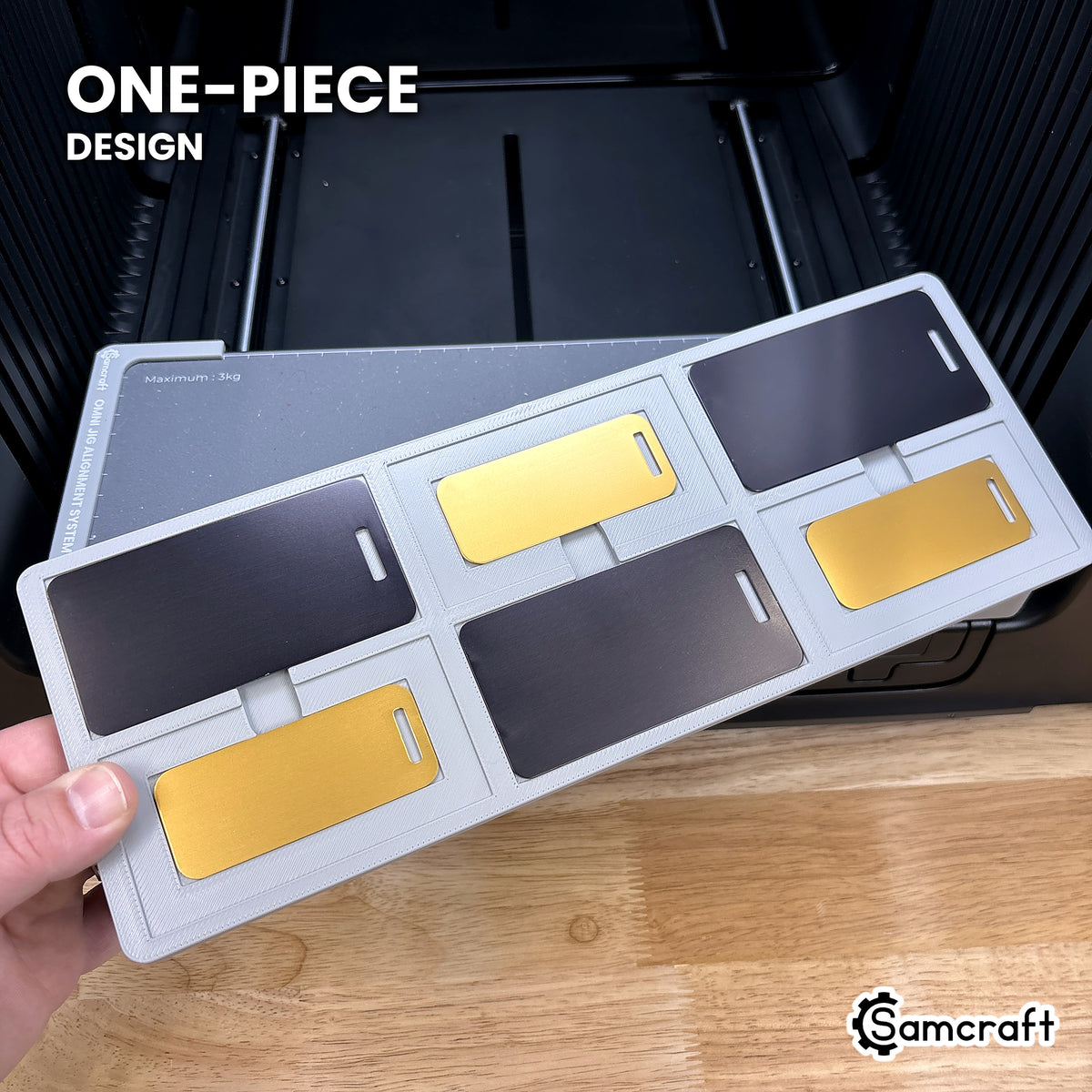 Hand holding the one-piece Samcraft metal luggage tag jig for the xTool Omni, six tag pockets in a single molded tray.
